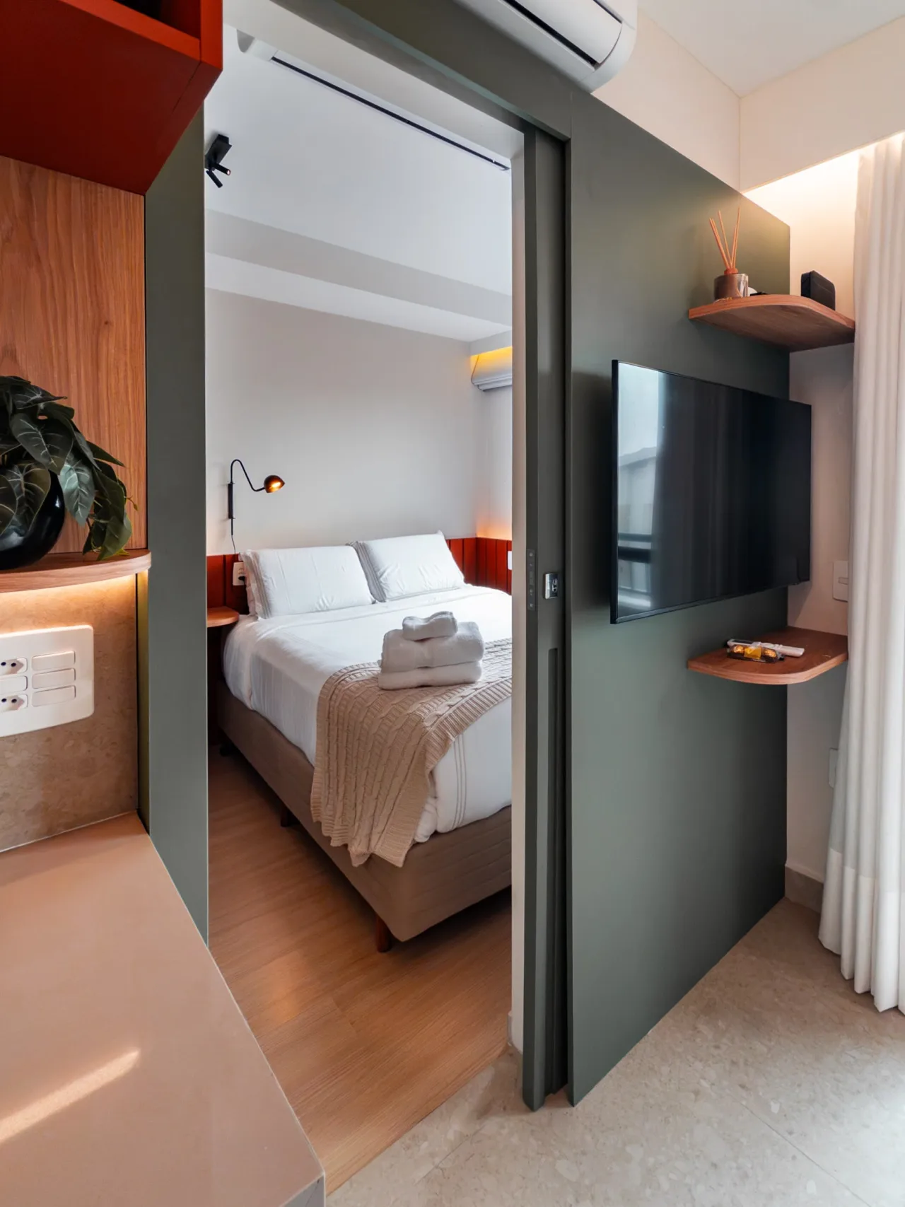 Quarto reformado com cama de casal, cabeceira estofada e luminária de leitura
