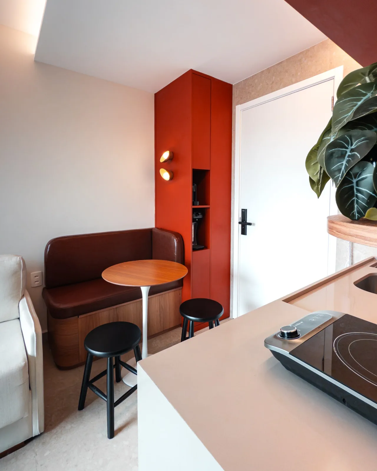 Sala de jantar com mesa redonda, banquetas e marcenaria laranja