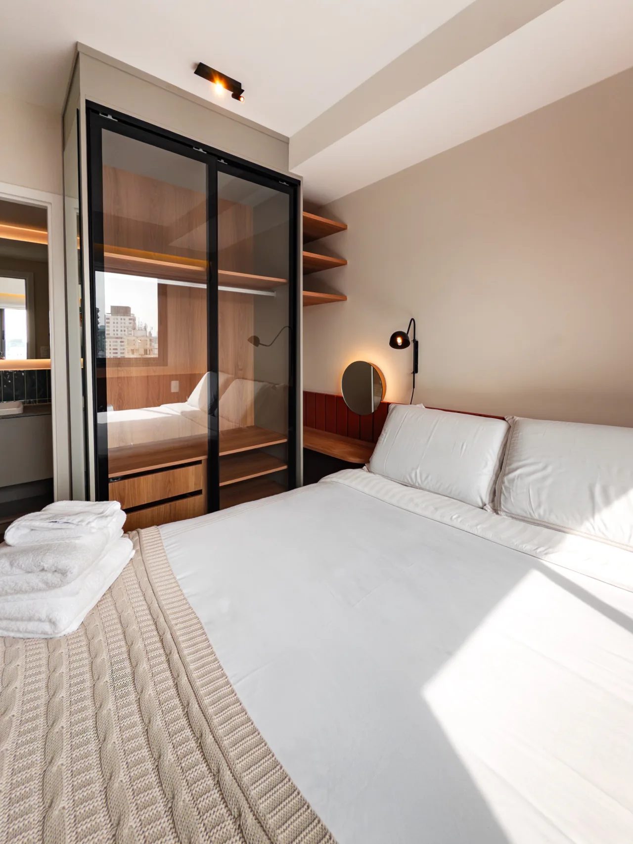 Quarto com cama de casal e closet com portas de vidro