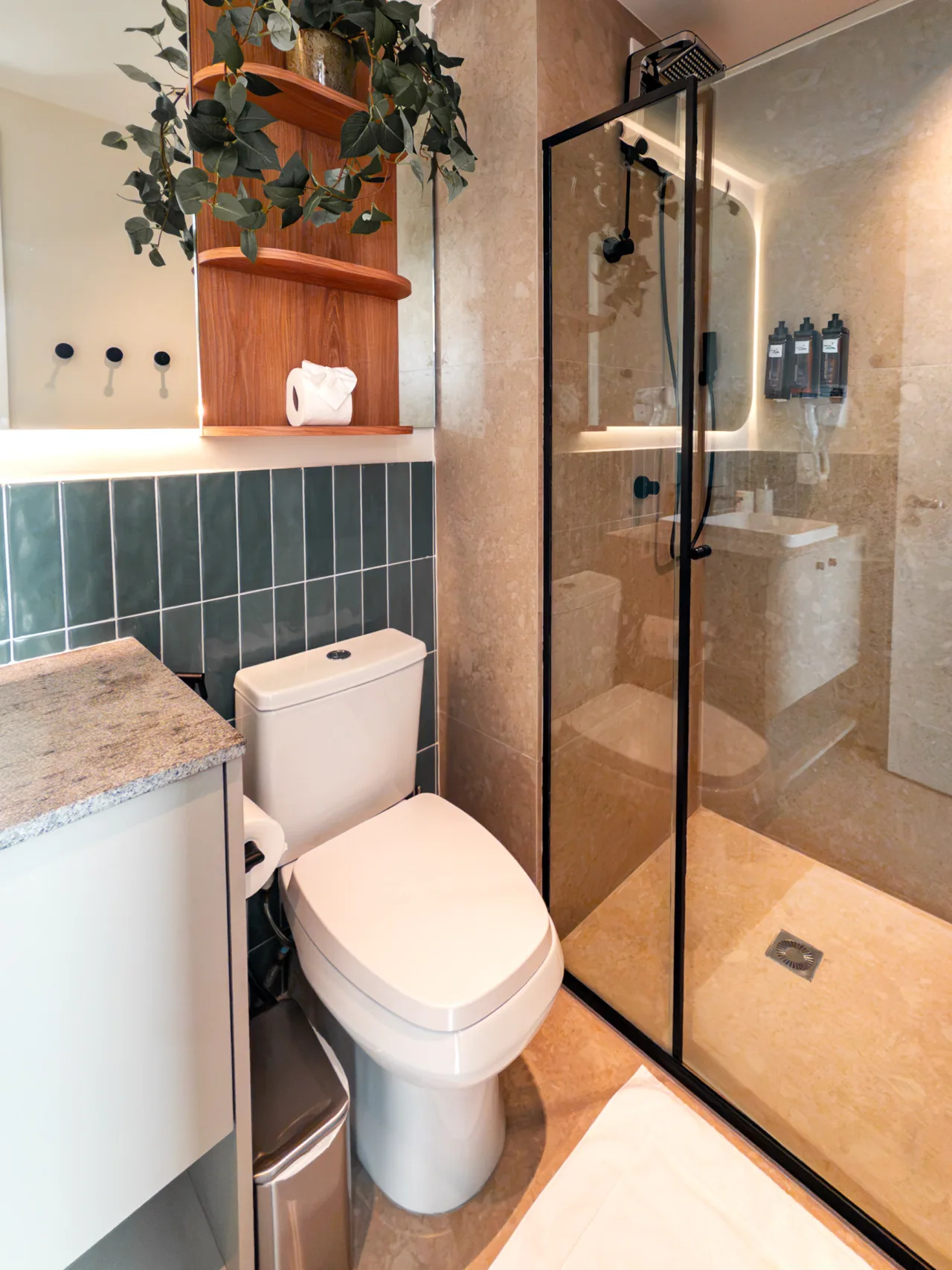 Banheiro com box de vidro, bancada em granito e revestimento verde