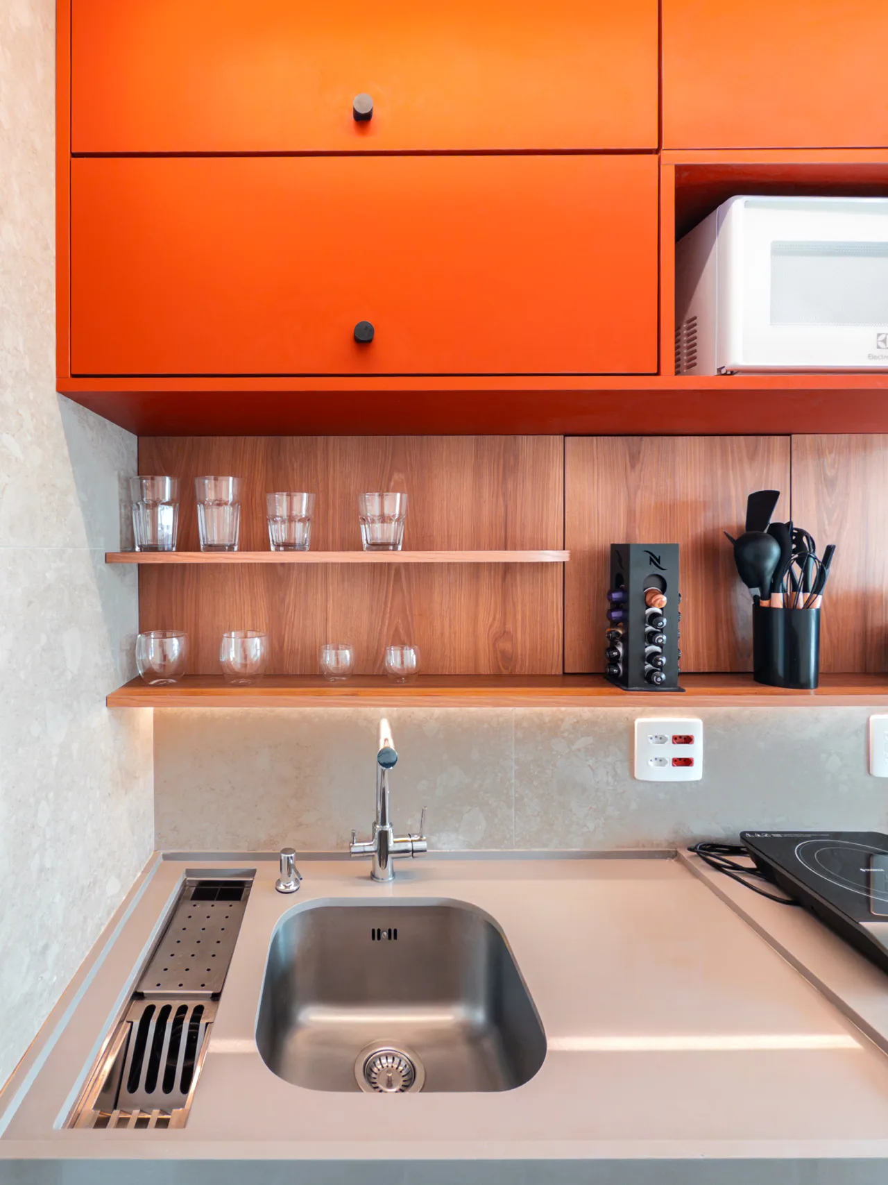 Cozinha com pia, cooktop e prateleiras com utensílios organizados