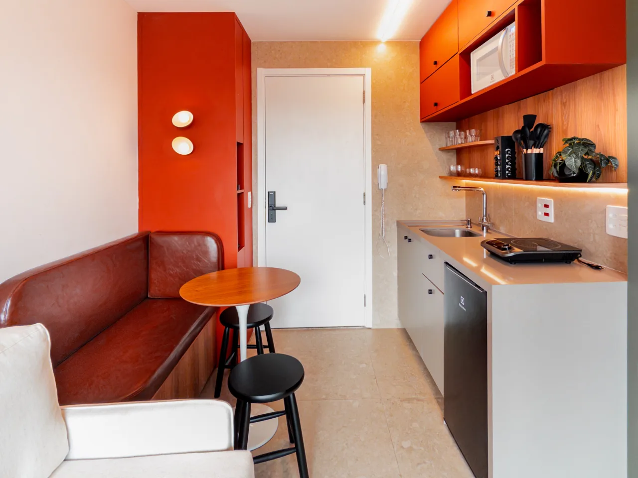 Sala e cozinha integradas com marcenaria laranja e bancada completa