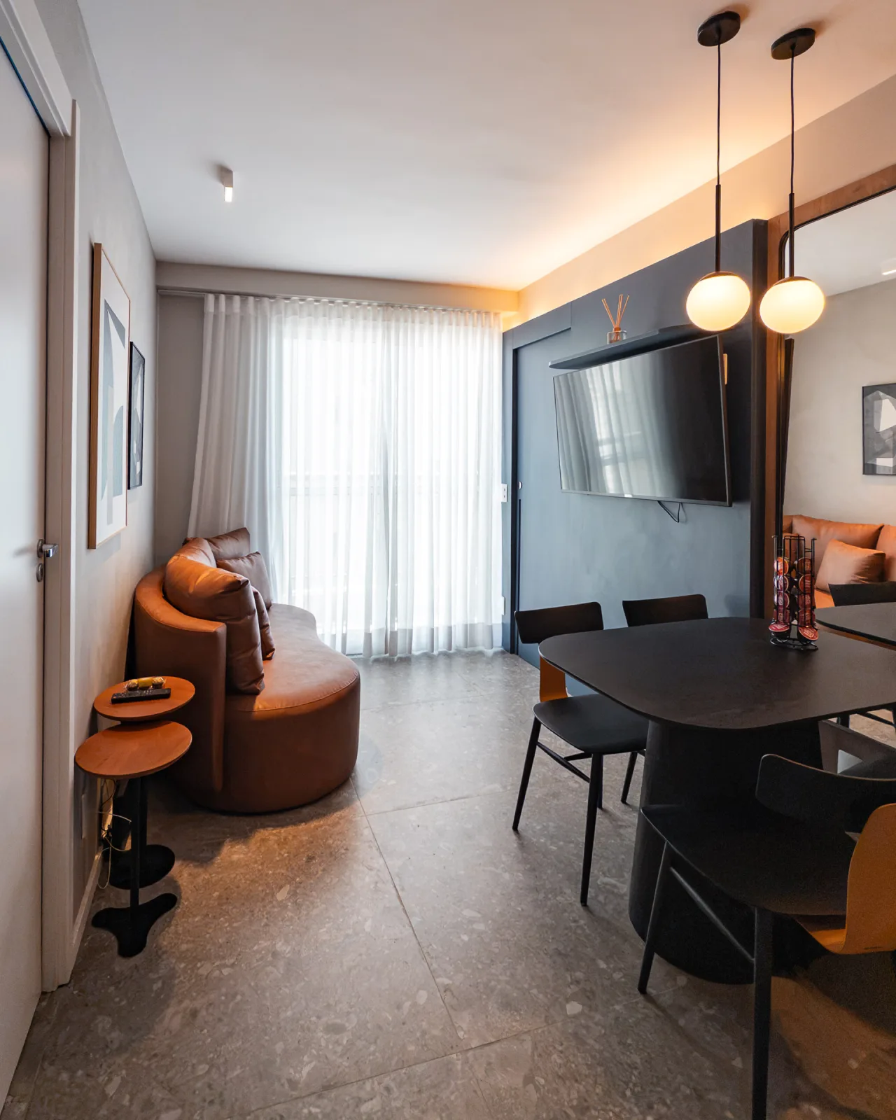 Sala de estar e jantar integradas com poltrona de couro e TV na parede azul