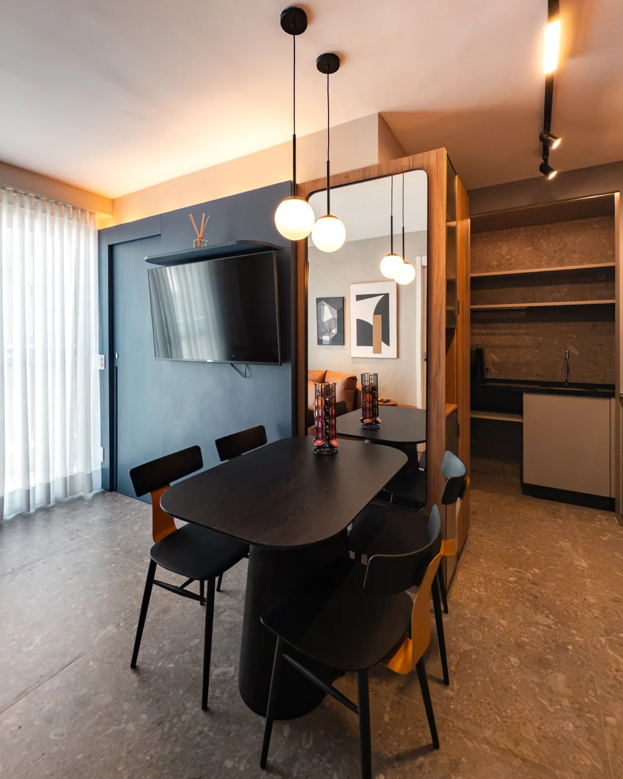 Sala de jantar com mesa oval preta e cristaleira de madeira com espelho