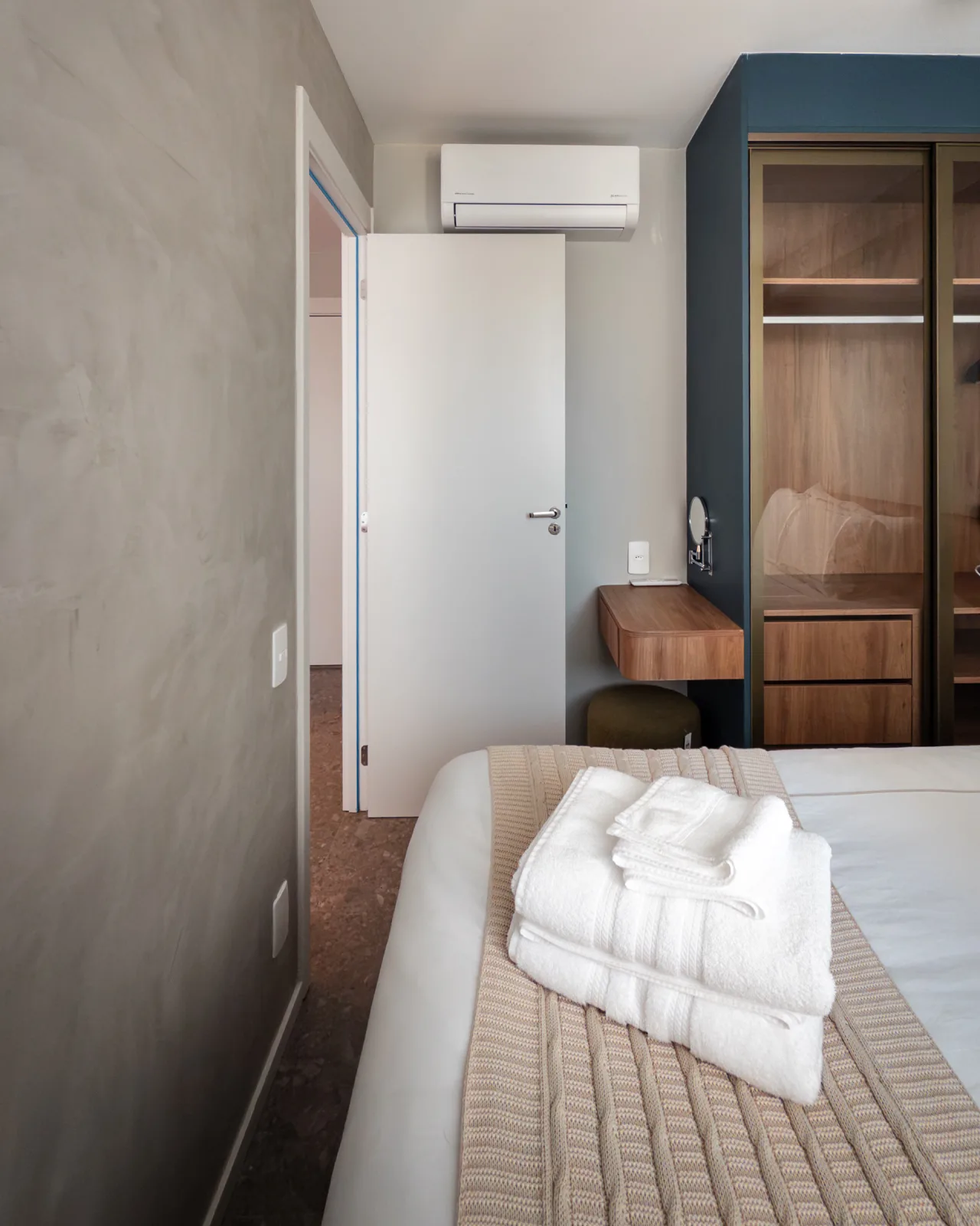 Quarto com closet envidraçado, ar-condicionado e toalhas sobre a cama